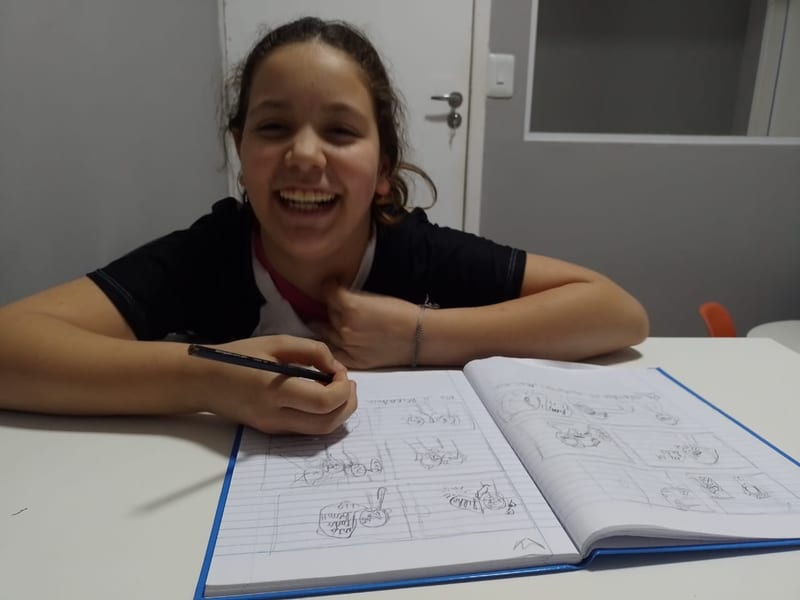 Criança escrevendo e criando uma história no caderno durante o atendimento